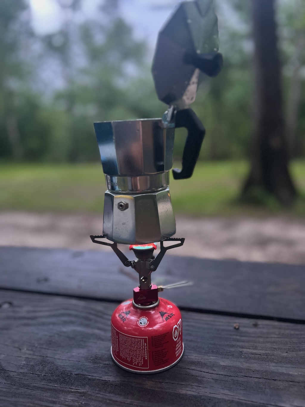 Camping moka pot brewing coffee on a small backpacking stove